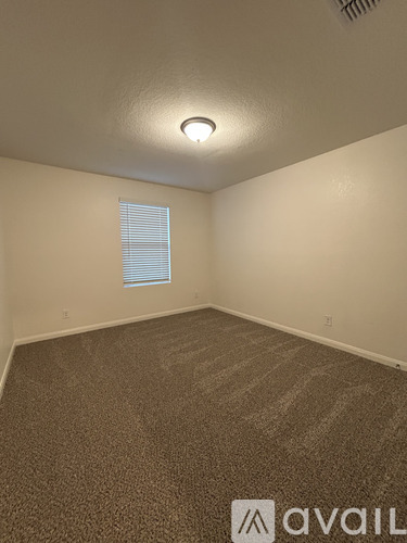 A room with a carpeted floor and a window with blinds.