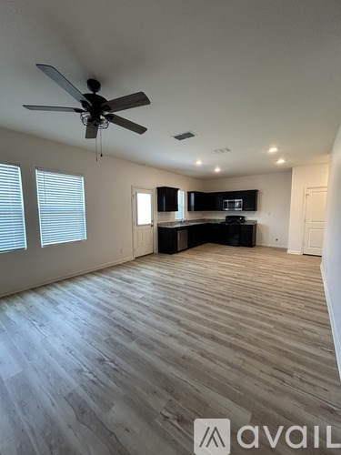 A spacious room with a ceiling fan and wooden flooring.