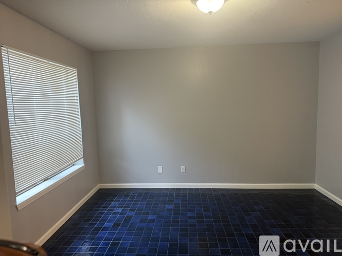 A room with a blue tile floor and a window with blinds.