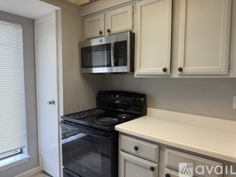 A kitchen with a black stove and white cabinets.