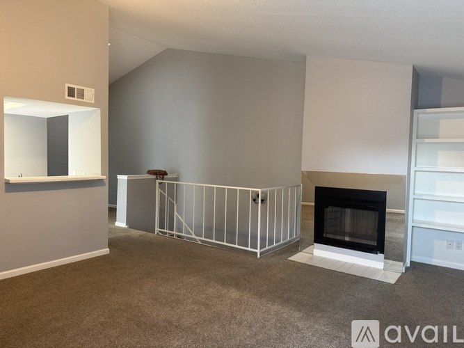 A living room with a fireplace and a grey carpet.