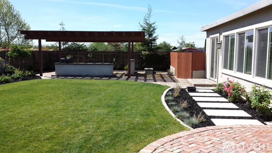 A backyard with a white hot tub and a brick walkway.