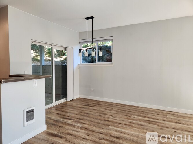 A room with wooden flooring and a window with a view of trees.