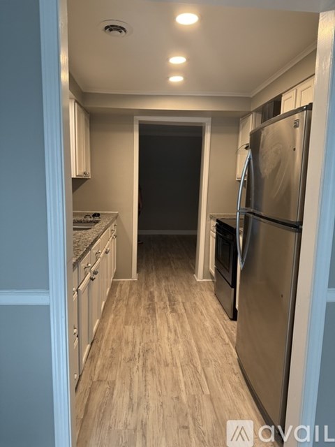 A kitchen with a refrigerator, oven, and cabinets.