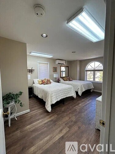 A bedroom with two beds and a window.