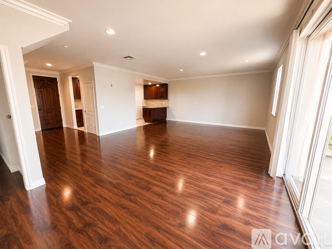 A spacious room with wooden flooring and white walls.