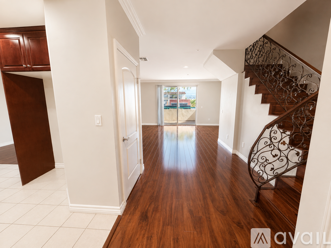 A long hallway with a staircase on the right and a doorway leading to a balcony.
