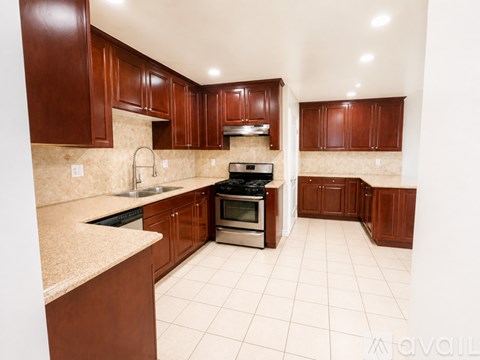 A kitchen with brown cabinets and a white tile floor.