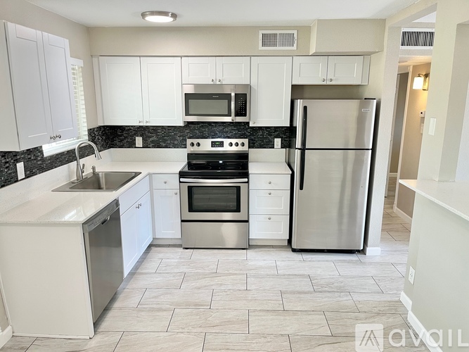A kitchen with white cabinets and a black countertop.