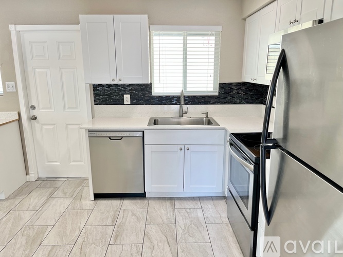 A kitchen with white cabinets and a black backsplash.