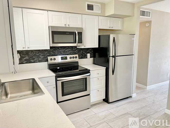 A kitchen with white cabinets and a black refrigerator.