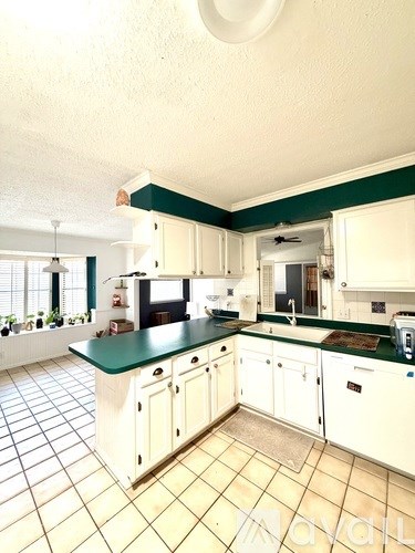 A kitchen with white cabinets and green countertops.
