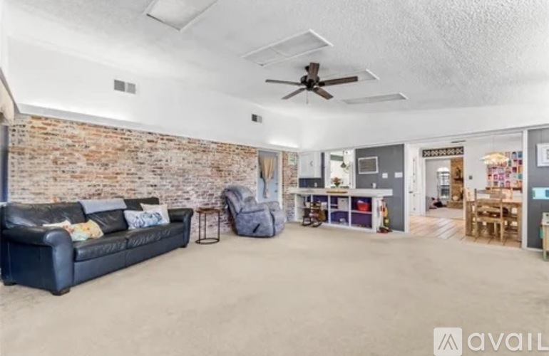 A living room with a brick wall and a ceiling fan.