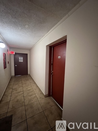 A hallway with a red door and a sign on the wall.