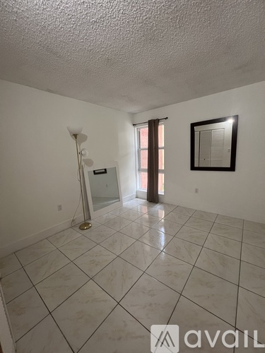 A spacious room with a tiled floor and a picture frame on the wall.