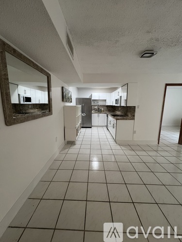 A hallway with a mirror on the wall and tiled flooring.