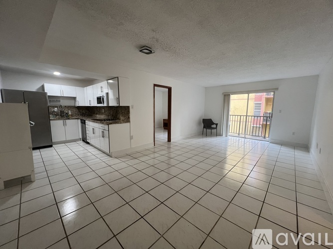 A spacious kitchen and living room with white tiled floors and a large window.