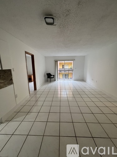 A long, empty hallway with white tiled floors and walls.