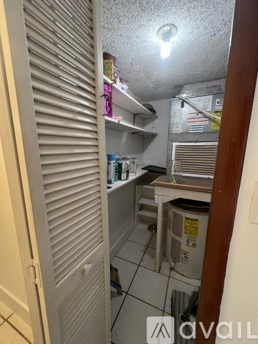 A small, cluttered kitchen with a white refrigerator and a white door.