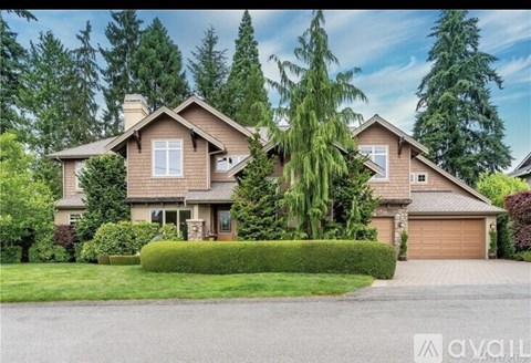 A large house with a garage is surrounded by greenery.