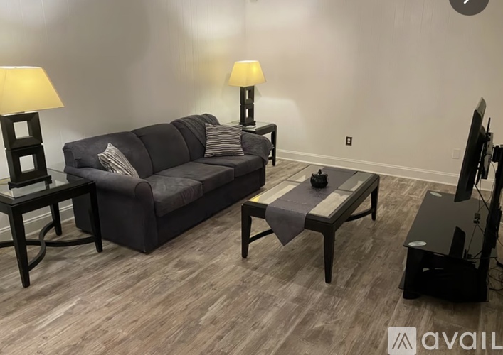 A living room with a grey couch, a small table, and a television.