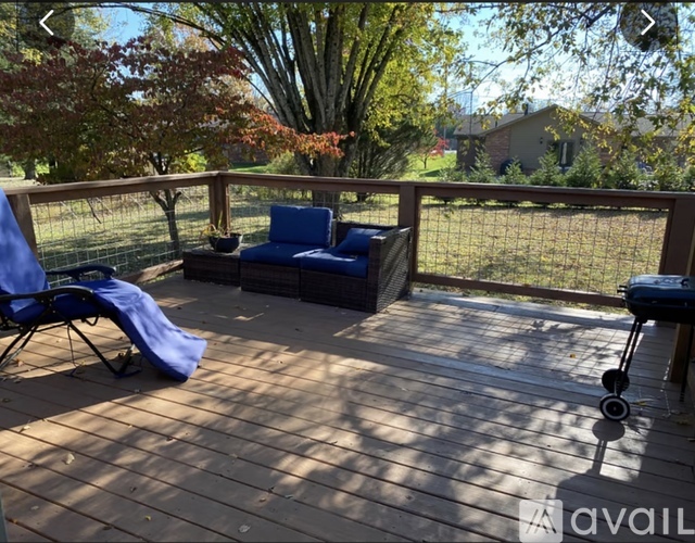 A blue chair is on a wooden deck with a grill and a table.
