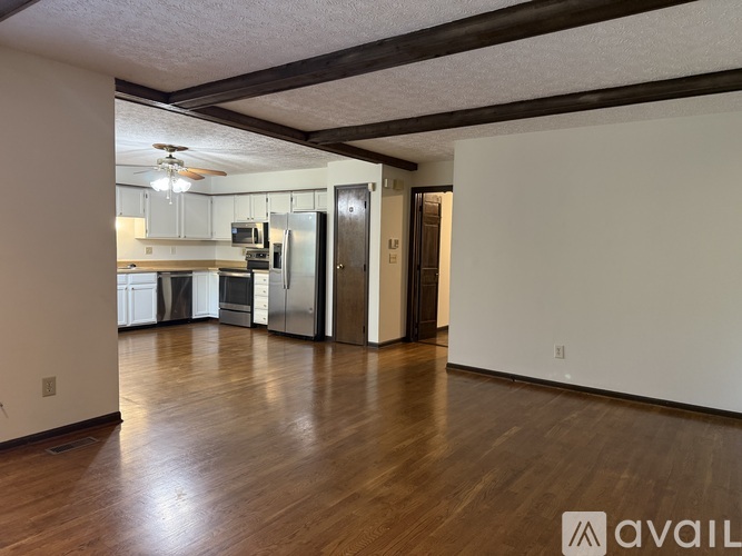 A kitchen with white cabinets and a refrigerator is visible through a glass door.
