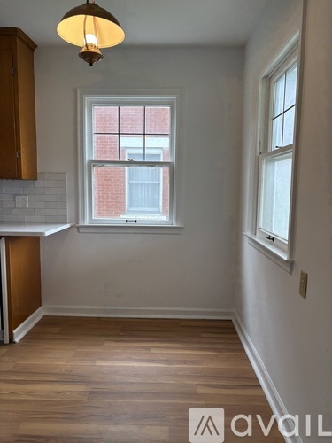 A room with wooden floors and a window with a view of a brick building.