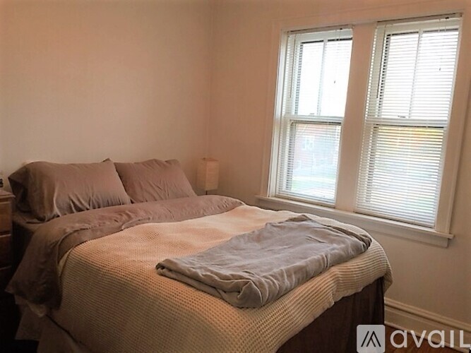 A bedroom with a bed and a window with blinds.