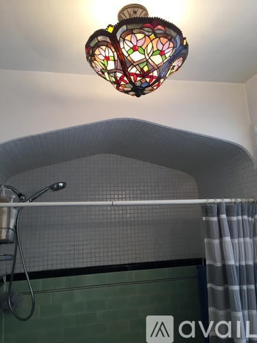 A bathroom with a green tiled wall and a shower curtain.