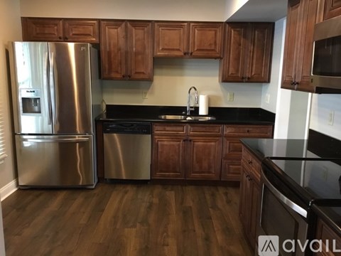 A kitchen with wooden cabinets and a stainless steel refrigerator.