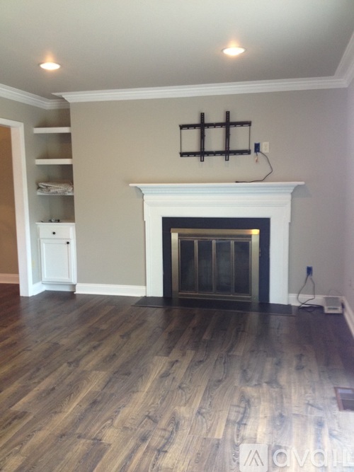 A living room with a fireplace and wood flooring.