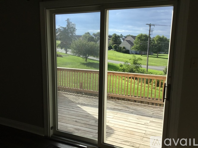 A view from inside a room looking out through a sliding glass door to a deck and a grassy yard.