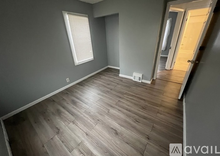 A room with wooden flooring and a window with blinds.
