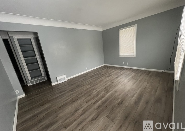 A room with wooden flooring and a window with blinds.