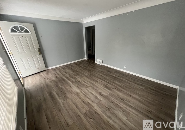 A room with wooden flooring and a white door.