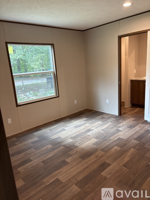 A room with wooden flooring and a window overlooking a parking lot.