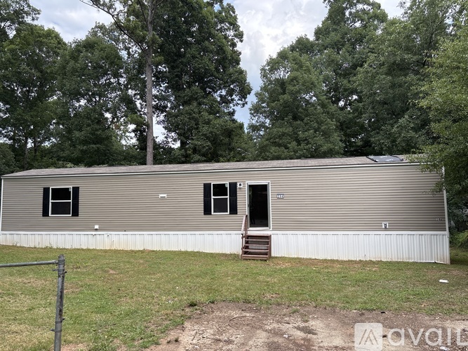 A grey metal building with a door and windows is surrounded by trees.
