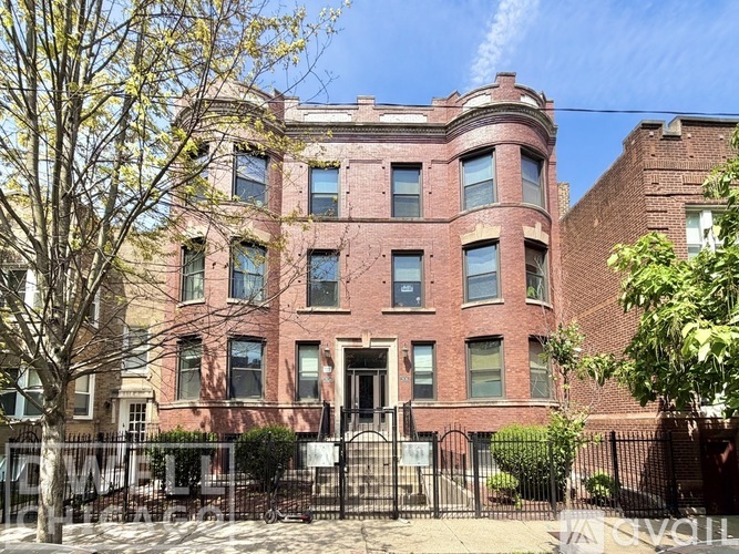 A red brick building with a black fence in front.