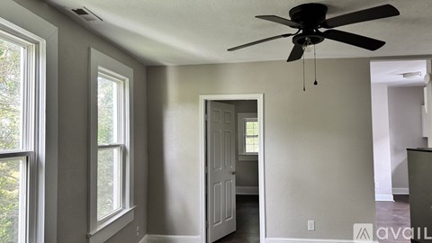 A room with a ceiling fan and a door leading to another room.