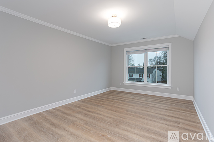 A room with wooden flooring and a window showing a view of buildings outside.
