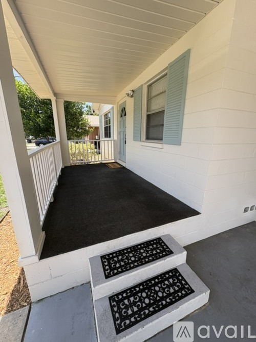 A porch with a black carpet and a white railing.
