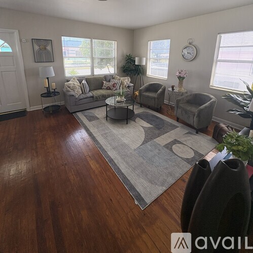 A living room with a grey sofa, two armchairs, a coffee table, and a rug.