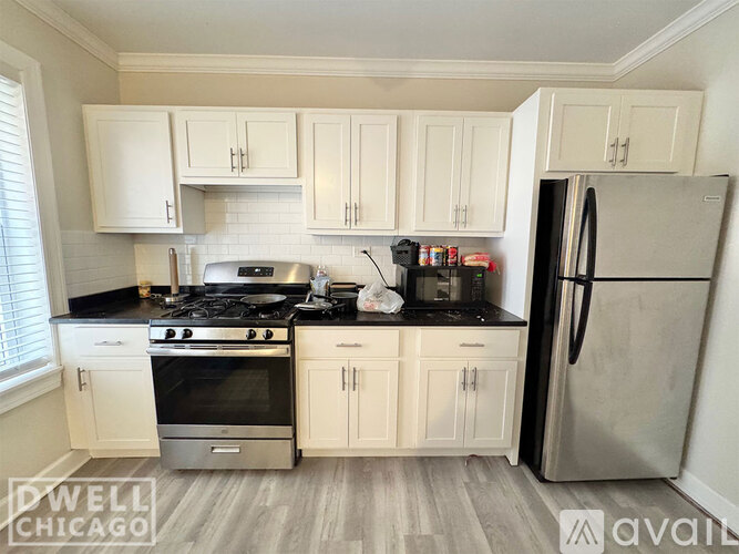 A kitchen with white cabinets and a black countertop.