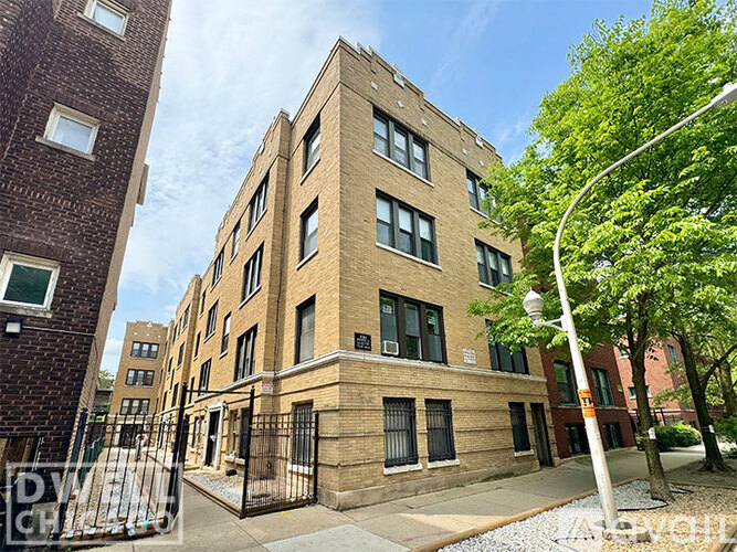 A tall brick building with a black gate in front.