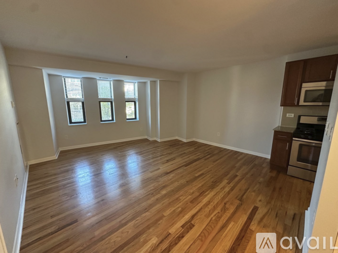 A room with wooden flooring and a kitchenette in the corner.