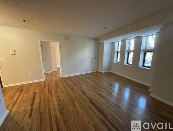 A room with wooden flooring and a window with blinds.
