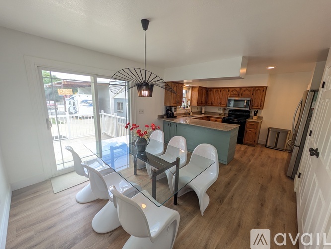 A modern kitchen with a glass table and white chairs.