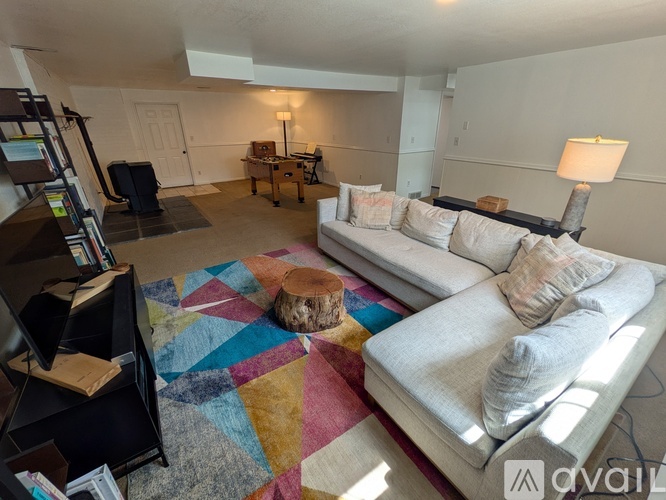 A living room with a white couch and a colorful rug.