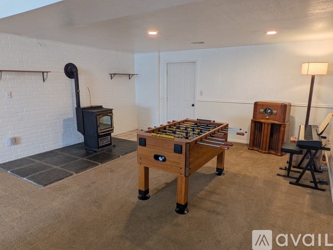 A room with a pool table, a wood-burning stove, and a foosball table.